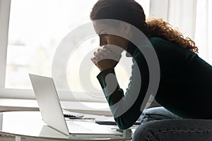 Thoughtful hispanic woman sit by home laptop consider on debt