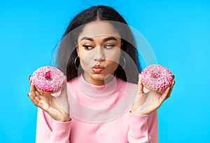 Thoughtful hungry woman choosing between donuts photo