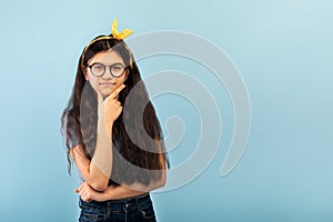 Thoughtful Indian teen girl looking at camera with serious face expression on blue studio background, copy space