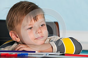 A thoughtful little boy at the desk