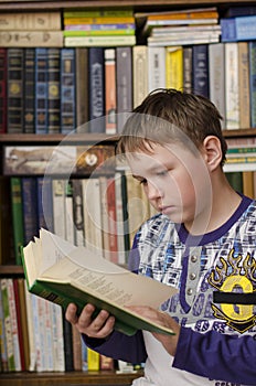 Thoughtful little boy reading book in the library