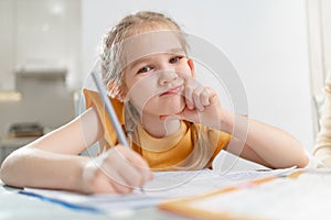 A thoughtful little schoolgirl does her homework.