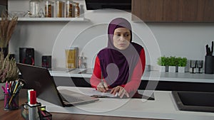 Thoughtful lovely middle eastern woman working on business startup in domestic kitchen