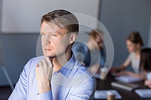 Thoughtful male employee looks in distance thinking about succes