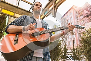 Thoughtful male guitarist training play on street