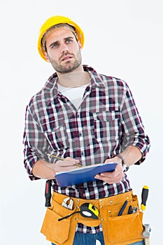 Thoughtful male repairman writing on clipboard