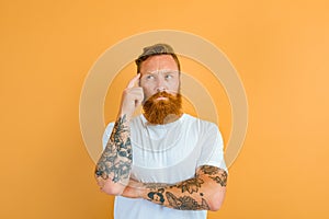 Thoughtful man with beard, tattoo and white t-shirt