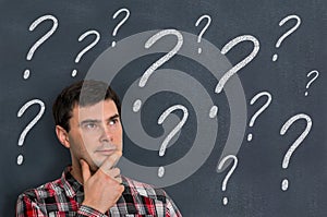 Thoughtful man and blackboard with question marks