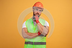 Thoughtful man builder construction touches chin, thinks over new idea for building, works as repairman, wears orange protective