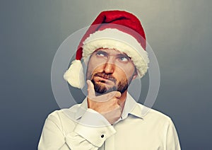 Thoughtful man in christmas hat looking up