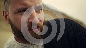 Thoughtful man face looking away on nature background. Handsome bearded guy.