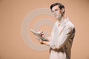 Thoughtful man in glasses holding notebook and pen isolated