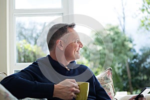 Thoughtful man having cup of coffee in living room