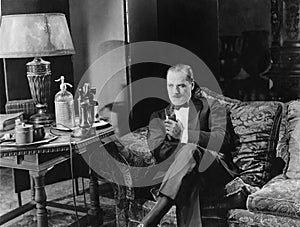 Thoughtful man having a drink on couch