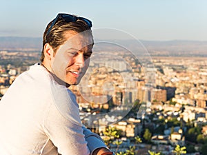 Thoughtful man in his thirties looking down at a panoramic view of the city