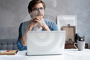 Thoughtful man looking away while sitting at his working place in office