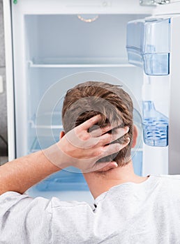 Thoughtful man looking in empty refrigerator