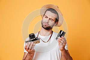 Thoughtful man looking at his camera while holding lens