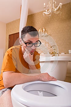 Thoughtful man looking into the toilet bowl