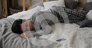 Thoughtful man lying on bed and using mobile phone