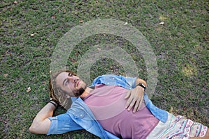 Thoughtful man lying on grass with hand behind head