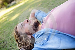 Thoughtful man lying on grass with hand behind head