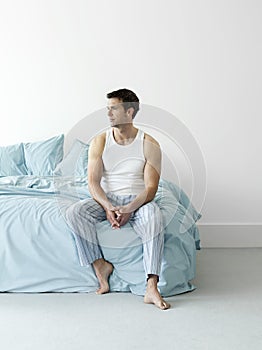 Thoughtful Man In Nightwear Sitting In Bed photo