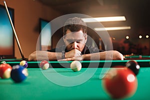 Thoughtful man plays billiards.