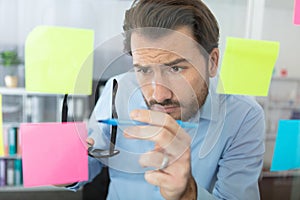 thoughtful man reading sticky notes in office