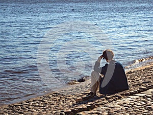 Thoughtful man sitting on the shore.