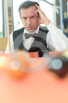 thoughtful man with suit sitting posing in billiard pool