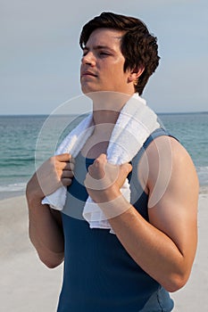 Thoughtful man with towel standing at beach