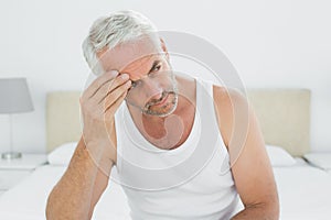 Thoughtful mature man sitting in bed