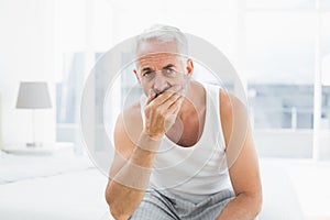 Thoughtful mature man sitting in bed