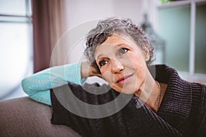 Thoughtful mature woman sitting on sofa