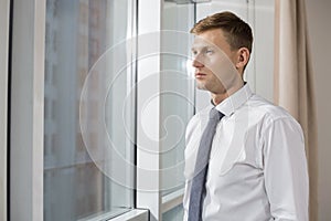 Thoughtful mid adult businessman looking through window at home