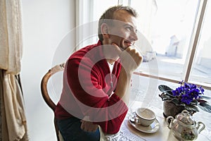 Thoughtful mid adult man sitting at table in cafe