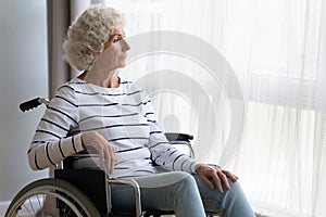 Thoughtful middle aged old hoary woman sitting in wheelchair.