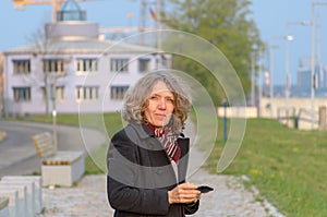 Thoughtful middle-aged woman holding her mobile