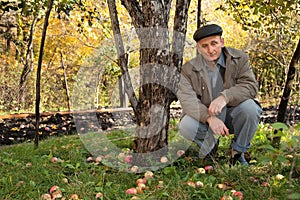 Thoughtful middleaged man sit under apple-tree