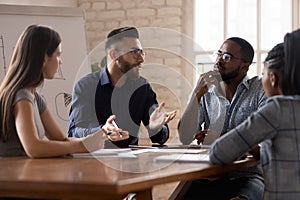 Thoughtful millennial diverse colleagues discuss ideas at briefing