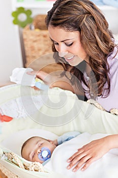 Thoughtful mother rocking his baby lying