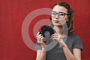 Thoughtful observant young woman photographer over a red wall