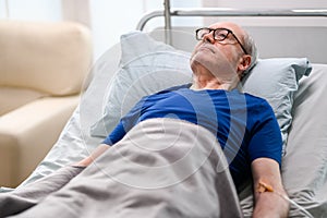 Thoughtful old man laying down on bed