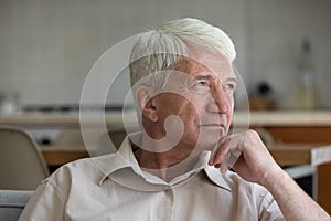 Thoughtful older age grandpa sit on couch look far away