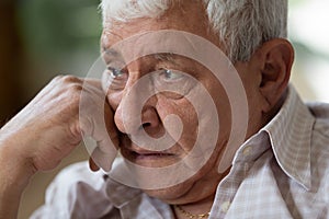 Thoughtful older retired man propping head with hand.