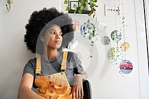 Thoughtful pensive African lady looking through window sitting at home, in cafe.