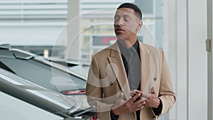 Thoughtful pensive guy male businessman African American man client buyer think choose new automobile in auto salon