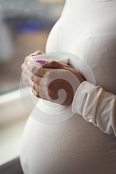 Thoughtful pregnant woman looks out the window