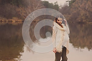 Thoughtful pregnant woman in soft warm cozy outfit walking outdoors